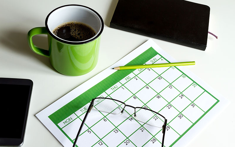 A calendar with coffee, glasses, and a smartphone.