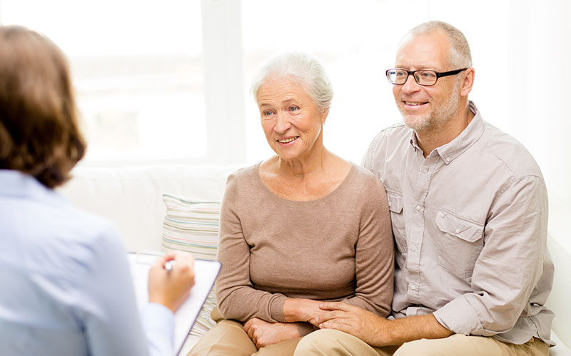 A smiling happy senior couple in couples therapy with a counselor.