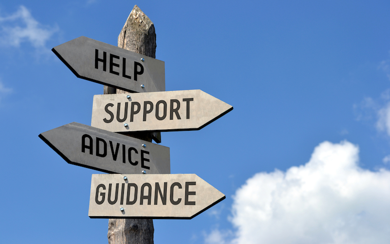 Wooden signpost with four arrows - "help, support, advice, guidance